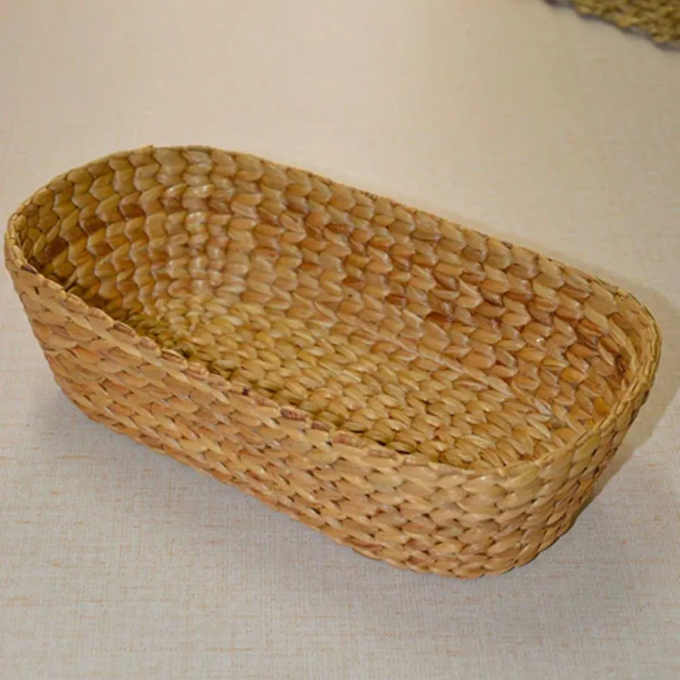 Handwoven oval water hyacinth bread basket with textured scale pattern, natural tone.