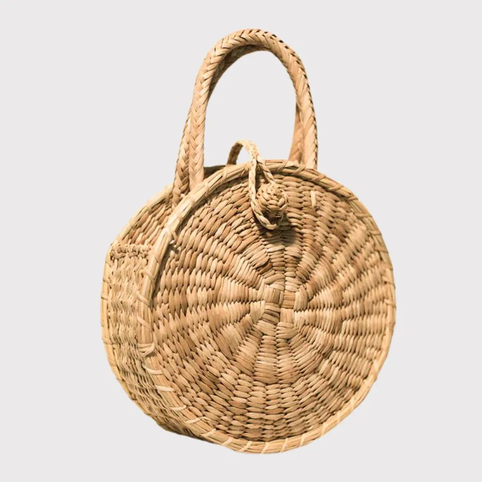 Circular spiral-woven seagrass handbag with knotted closure, ethically crafted by EHM Vietnam.