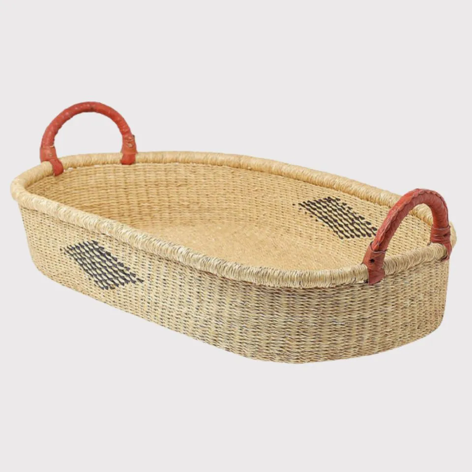 Oval seagrass changing basket with red leather-wrapped handles, designed for premium kid basket manufacturing.