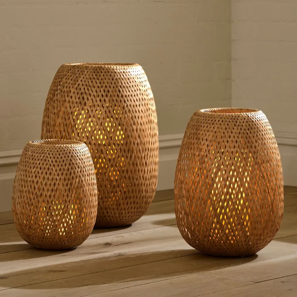 Set of three handwoven bamboo lanterns in different sizes, glowing warmly – made by EHM Vietnam