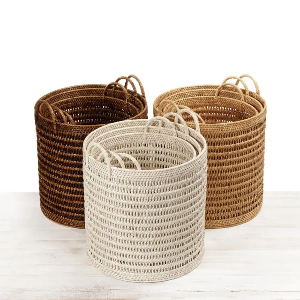 Cylindrical rattan storage baskets with loop handles in three natural shades – EHM custom manufacturing.