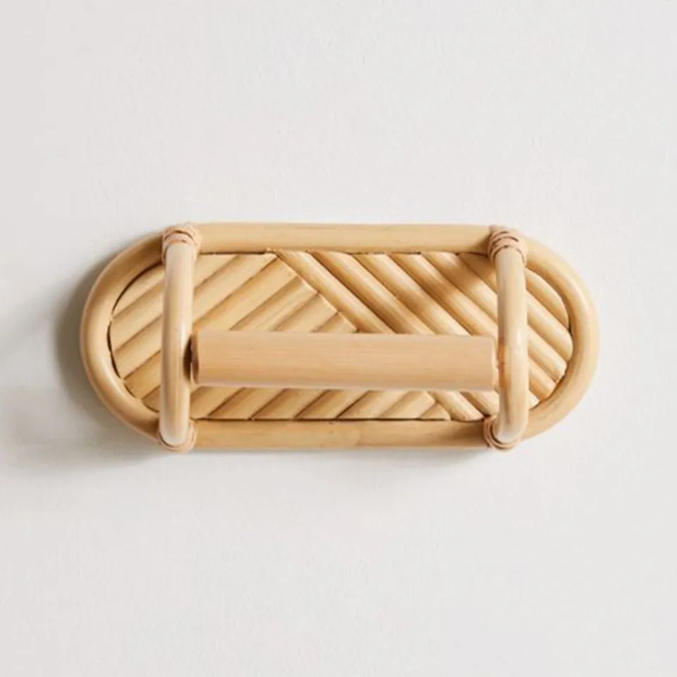 Wall-mounted rattan toilet paper holder with geometric weave pattern and curved support arms.