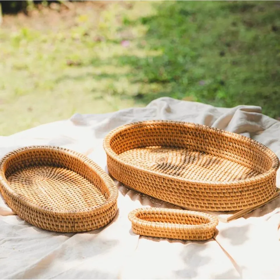 Handcrafted rattan oval trays in three sizes, tightly woven natural rattan, rustic outdoor setting – artisanal rattan tray manufacturing